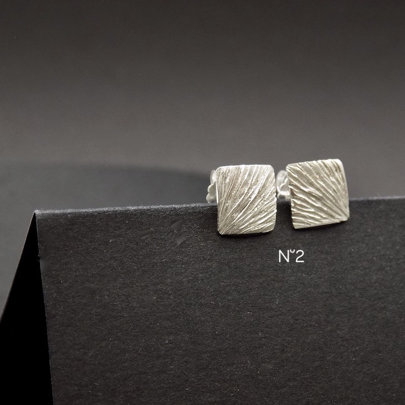 Photo d'une paire de boucles d'oreille en argent 925. Les boucles sont carrées et petites